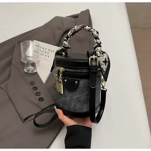 Detail of bucket bag featuring grey denim patchwork and a silk scarf wrapped handle