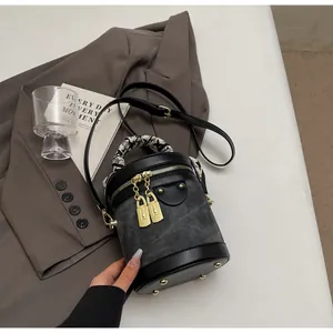 Detail of grey denim bucket bag with silk scarf handle and golden metal hardware