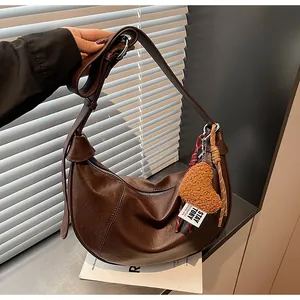 Détail du sac hobo croissant marron foncé avec pendentif coeur en peluche jaune