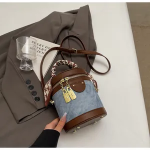 Detail of blue denim bucket bag with brown leather trim and houndstooth scarf handle