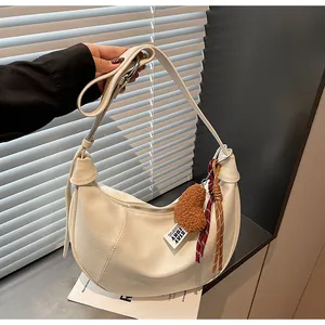 Détail du sac hobo croissant crème avec texture PU mate et pendentif cœur décoratif