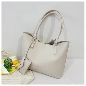 Detail view of large cream tote bag with matching envelope pouch and vertical stitching