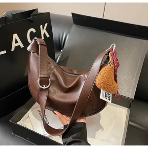 Détail du sac demi-lune marron avec breloque cœur en peluche dans son coffret cadeau