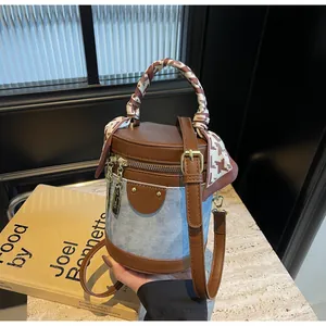 Detail of denim bucket bag with leather patchwork and houndstooth silk scarf handle