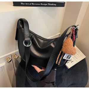 Détail du sac croissant noir avec charm cœur en peluche marron et boucles argentées
