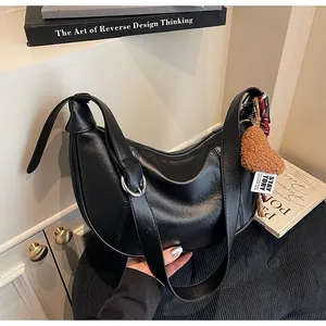 Détail du sac hobo en cuir noir avec boucle argentée et charm cœur en peluche