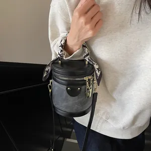 Chic black leather and grey denim bucket bag with scarf-wrapped handle and gold chain