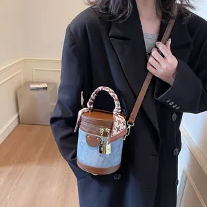 Blue denim bucket bag with brown leather trim and silk scarf wrapped handle