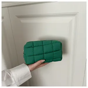 Détail d'une pochette matelassée verte avec surpiqûres carrées et fermeture dorée