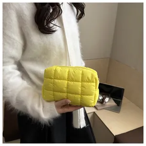 Detail of yellow quilted puffer makeup bag with metal zipper and grid texture