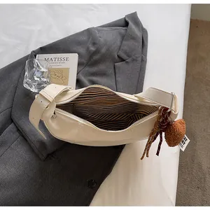 Détail du sac croissant avec doublure rayée et pendentif décoratif en peluche