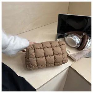Detailed view of a brown quilted puffer cosmetic bag on a wooden desk with office accessories