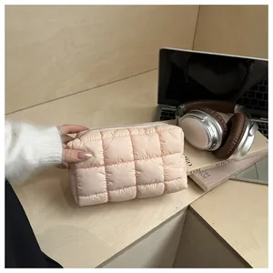Détail d'une trousse à maquillage matelassée rose avec fermeture éclair sur un bureau