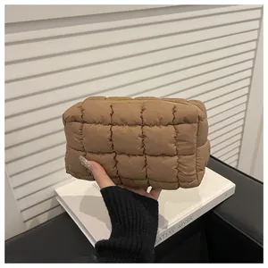 Détail d'une trousse de maquillage marron matelassée avec couture carrée et zip