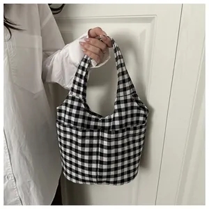 Detail of checkered canvas tote bag featuring two front pockets and minimalist handle