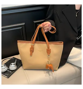 Detail van retro draagtas met olifantenhanger en tekst op stijlvol beige leder
