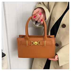 Close-up of brown leather handbag with gold heart buckle and beige trench coat styling