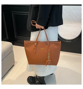 Detailweergave van bruine lederen tote bag met gouden letters en olifantenhanger