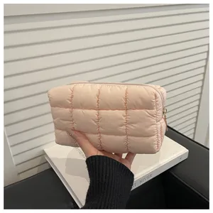 Gros plan sur une trousse à maquillage matelassée rose avec fermeture éclair dorée