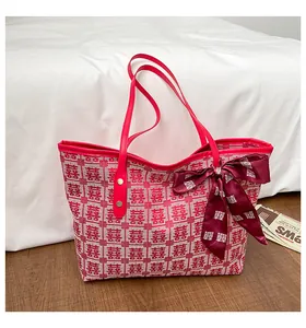 Détail du sac cabas en tissu rouge et blanc avec motif Xi et grand nœud décoratif