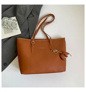 Detailweergave van de bruine draagtas met gouden gespen en een schattige olifantenhanger