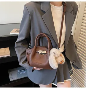 Detail of dark brown lychee leather handbag with silver clasp and plush rabbit charm