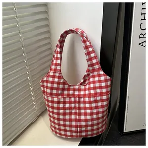 Detailed macro view of red gingham canvas tote bag with functional front pockets and thick fabric