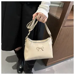 Close-up of cream PU leather handbag with a gold bow detail and metallic accents