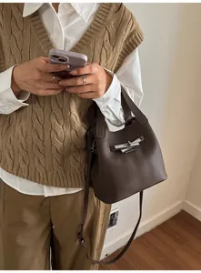 Vue détaillée du sac seau en cuir marron foncé avec fermoir rotatif argenté et lanière