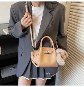Detail view of beige leather bucket bag with silver hardware and a plush rabbit charm