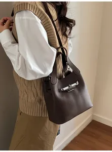 Détail du sac seau marron foncé avec texture en cuir litchi et fermoir en argent poli