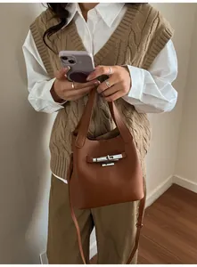 Vue détaillée du cuir grainé caramel et du fermoir rotatif en métal argenté du sac