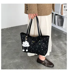 Dettaglio della borsa tote nera stellata con ciondolo a nuvola bianca e manici in pelle