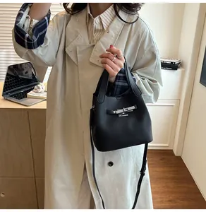 Détail d'un sac seau en cuir grainé noir avec fermoir rotatif en métal argenté brillant