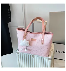 Dettaglio della borsa tote in tela rosa con stelle, manici con rivetti e ciondolo nuvola