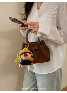 Close-up of retro brown suede bucket bag featuring a cute black plush puppy pendant