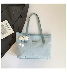 Dettaglio della borsa tote azzurra con stelle argentate e ciondolo a nuvola
