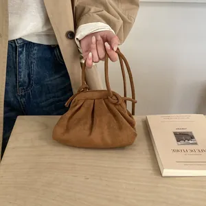 Gros plan d'un sac nuage en daim marron avec design plissé et fines anses rondes