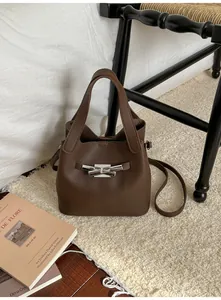 Détail du sac seau marron foncé avec texture grainée et boucle métallique argentée élégante