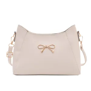 Elegant cream white faux leather shoulder bag with a gold bow buckle and adjustable strap