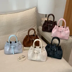 Multiple colors of textured bucket bags with detachable straps shown in a home setting