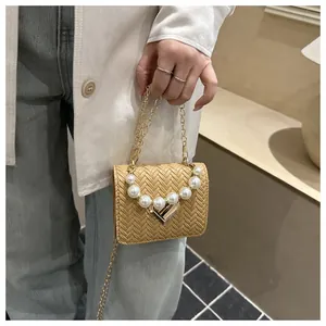 Detailed view of woven texture handbag with pearl handle and golden heart clasp