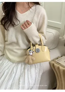 Borsa a conchiglia giallo pallido con ciondolo a orsetto e maglieria vintage minimalista
