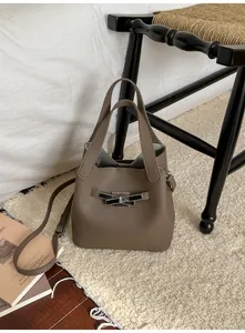 Détails d'un sac seau en cuir grainé marron avec anses sur un tapis moelleux