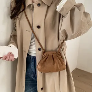 Détail d'un sac à main plissé en daim marron porté avec un trench-coat kaki