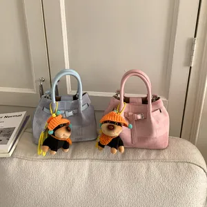 Detail of bucket bags in light pink and blue with cute dog plush charms on a sofa