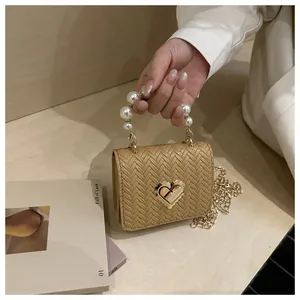 Close-up of woven texture mini bag with pearl handle and golden heart-shaped lock