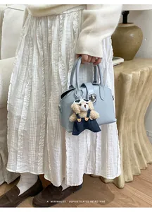 Borsa a mano in pelle azzurra con ciondolo a orsetto in uno stile retrò minimalista