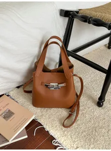 Détails du sac seau en cuir marron grainé avec boucle argentée et bandoulière réglable
