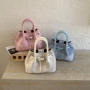 Detailed view of canvas bucket bags in pink, beige, and blue with plaid texture